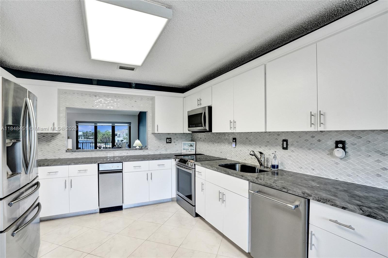 1101 South Riverside Drive, Unit 301 Pompano Beach, FL 33062 - Photo 15 of 40 a kitchen with granite countertop white cabinets and white appliances