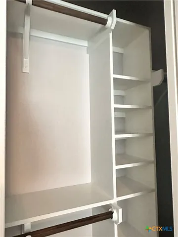 a view of walk in closet with empty racks