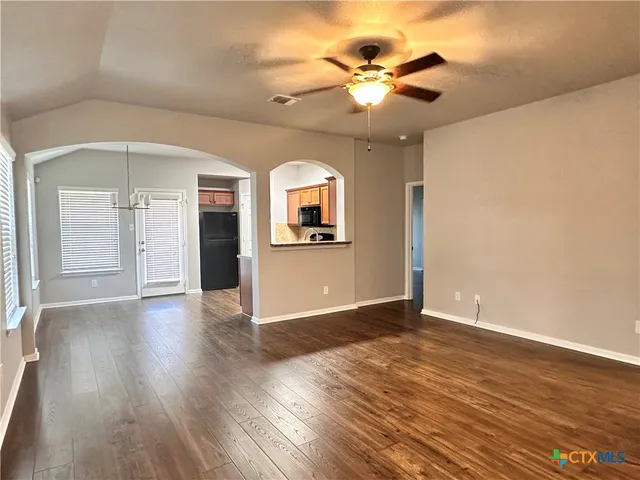 an empty room with wooden floor chandelier and glass door