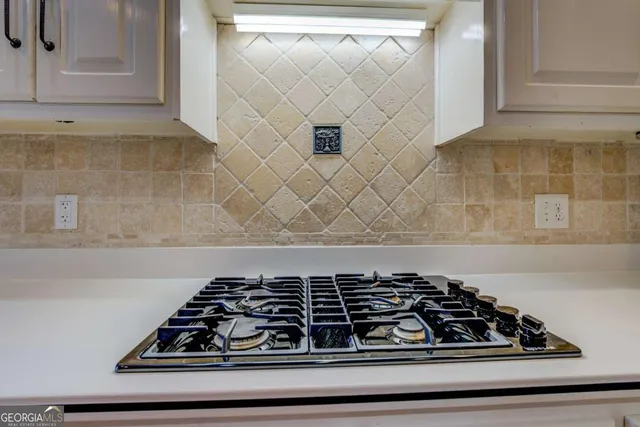a view of an empty room with chandelier fan and windows