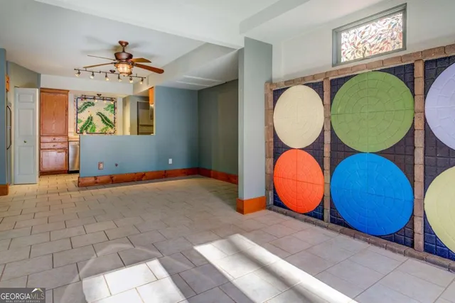 an empty room with chandelier fan and windows