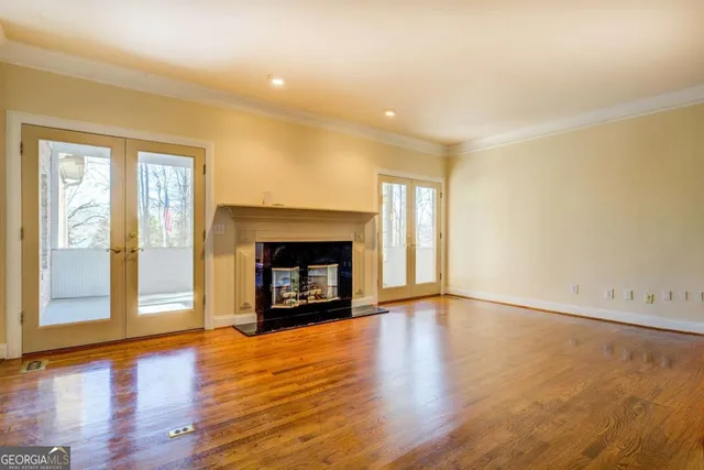 an empty room with wooden floor fire place and windows