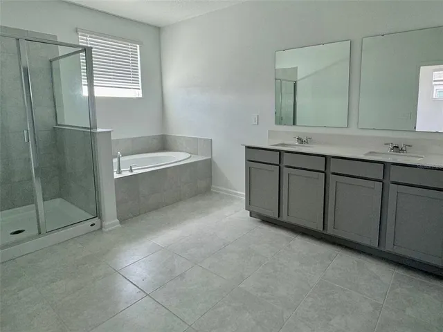 a spacious bathroom with a bathtub sink and mirror
