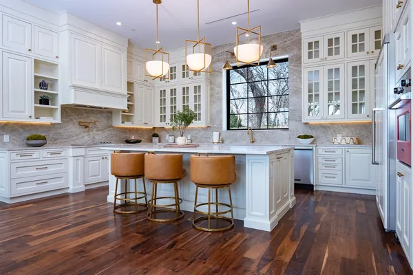 a kitchen with stainless steel appliances a dining table chairs stove and cabinets