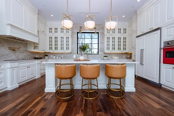 a kitchen with granite countertop a stove a sink dishwasher a dining table and chairs with wooden floor