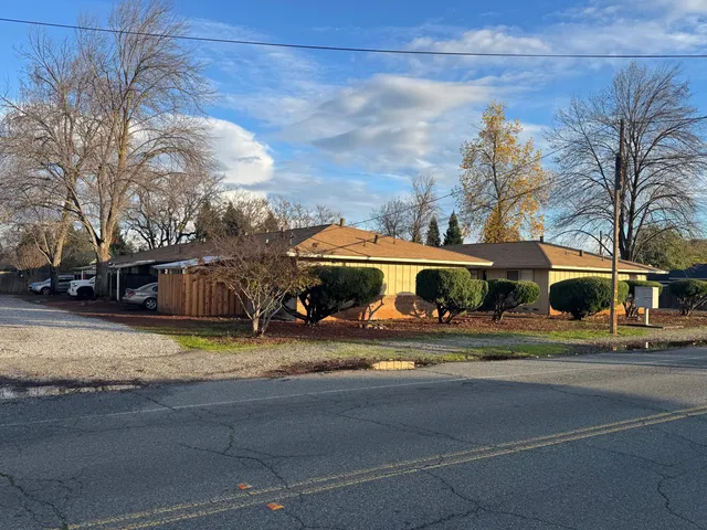 a view of a house with a yard and large trees