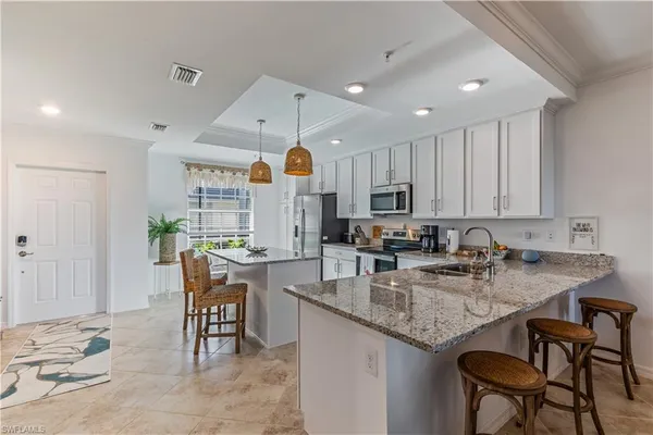 a kitchen with granite countertop a table chairs stove a sink and cabinets
