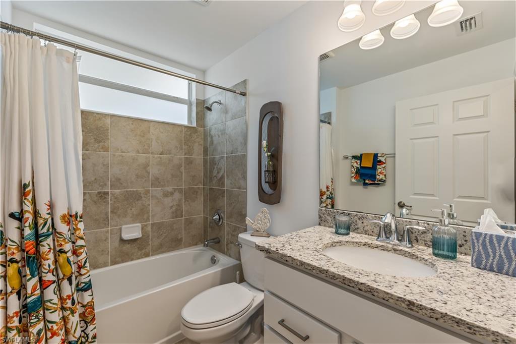 43031 Greenway Boulevard, Unit 1028 Babcock Ranch, FL 33982 - Photo 7 of 15 a bathroom with a granite countertop sink a toilet a mirror a bathtub and shower