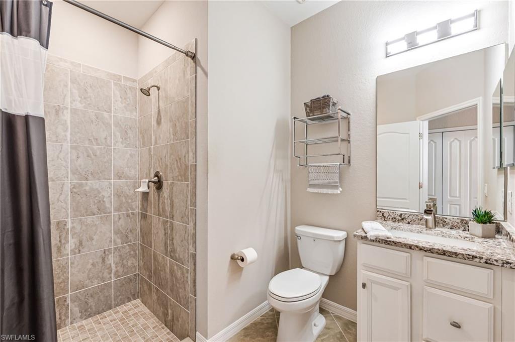 4686 Abaca Circle Naples, FL 34119 - Photo 30 of 47 a bathroom with a granite countertop sink toilet and shower