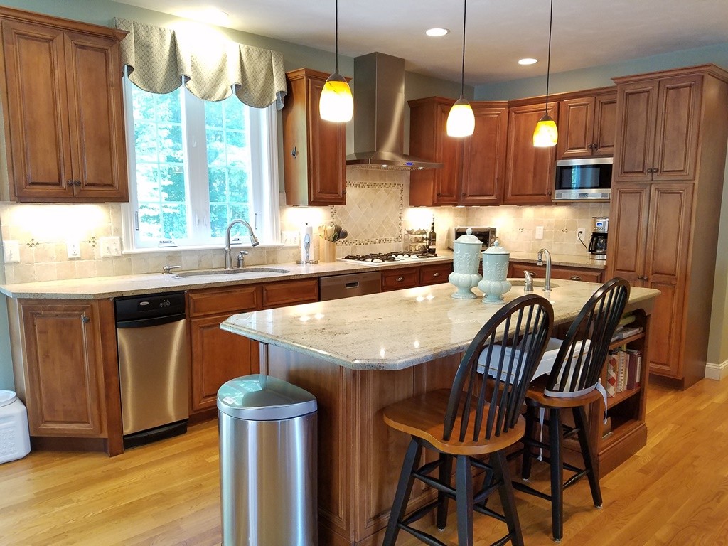 39 Ridgewood Street Ashland, MA 01721 - Photo 3 of 30 a kitchen with stainless steel appliances granite countertop a sink a microwave a dining table and chairs