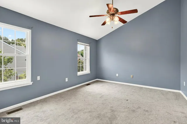 an empty room with windows and fan