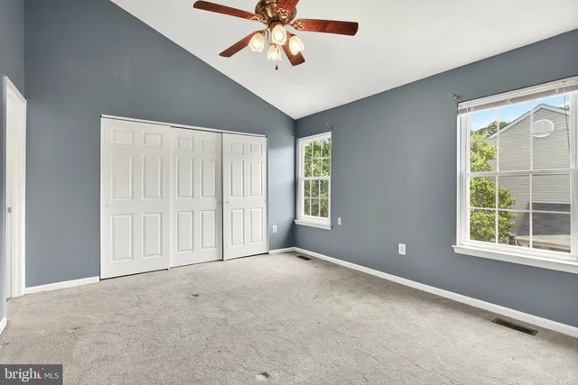 an empty room with windows and fan