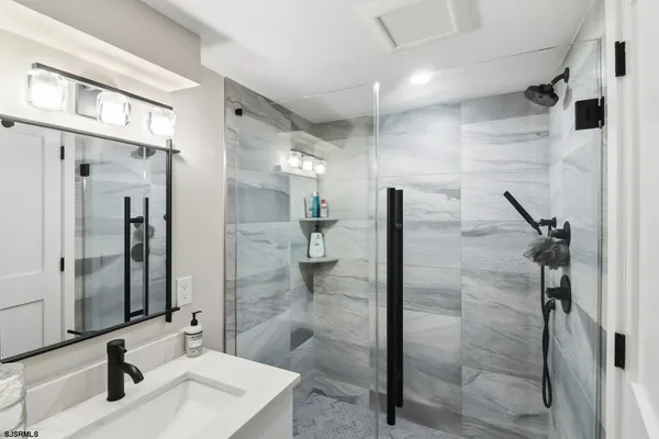 a bathroom with a sink shower and a mirror