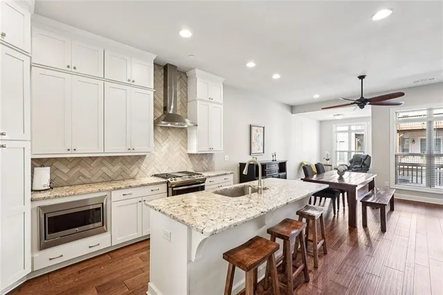 a kitchen with granite countertop white cabinets sink and chairs