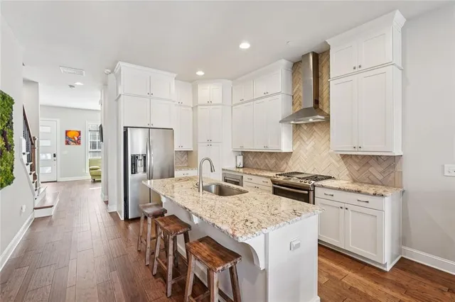 a kitchen that has a lot of white cabinets and stainless steel appliances