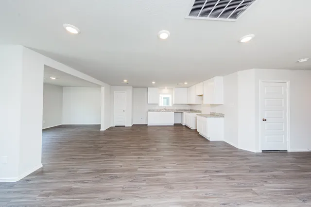a view of kitchen and empty room with wooden floor