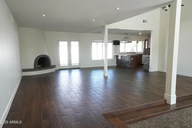 a view of a big room with wooden floor and a kitchen