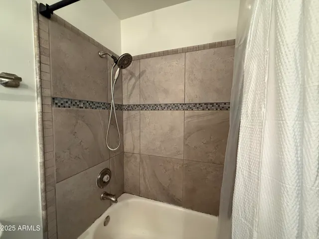 an empty room with a chandelier fan and windows