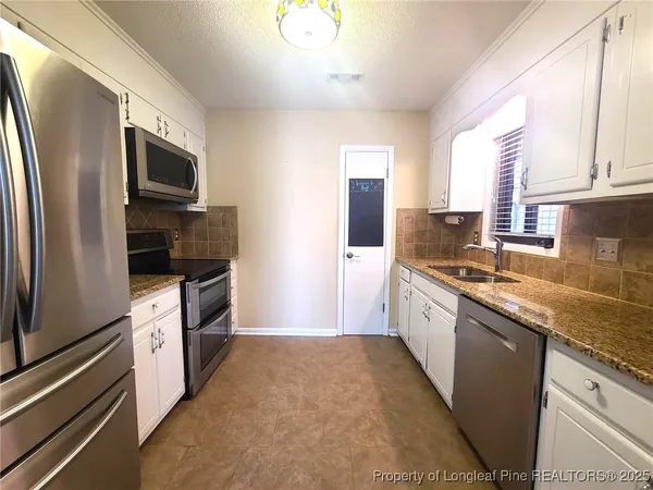 a large kitchen with stainless steel appliances granite countertop a refrigerator a stove a sink and a microwave