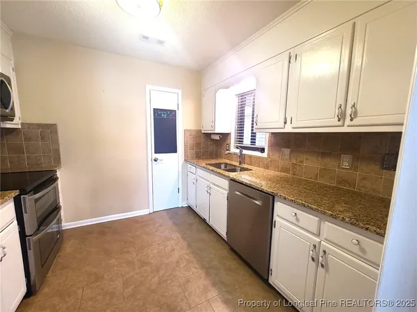a large kitchen with granite countertop a sink and a stove top oven