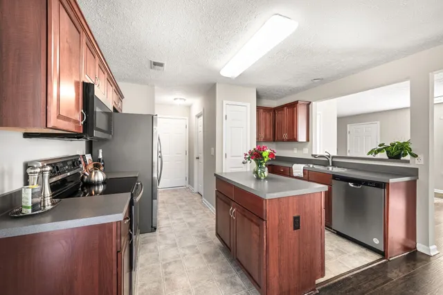 a kitchen with kitchen island granite countertop a sink stove and cabinets