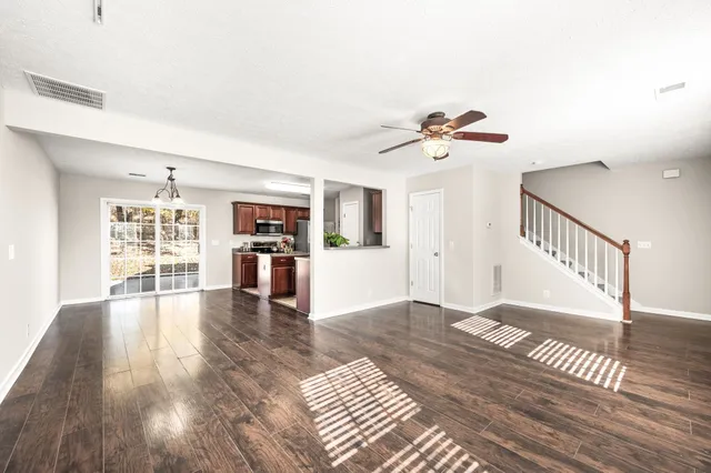 a view of an empty room with wooden floor and a ceiling fan