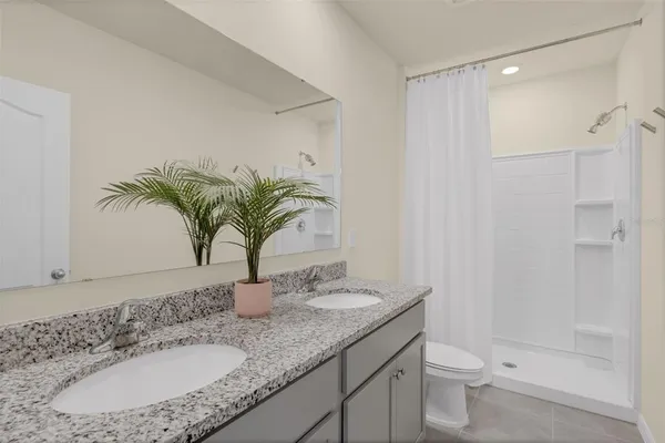 a bathroom with a granite countertop sink a toilet and shower