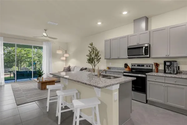 a kitchen with stainless steel appliances granite countertop a stove top oven a sink a dining table and chairs with wooden floor