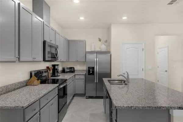 a kitchen with stainless steel appliances granite countertop a sink stove and refrigerator