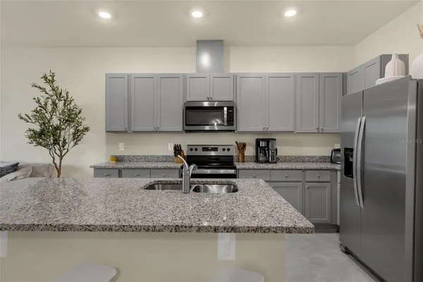 a kitchen with stainless steel appliances granite countertop a sink a stove a microwave a sink a refrigerator and a counter