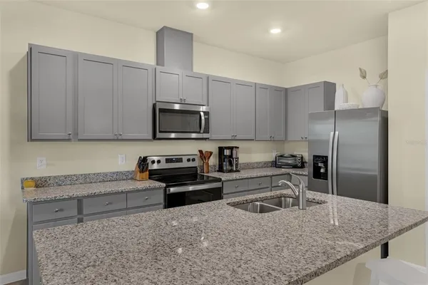 a kitchen with stainless steel appliances granite countertop a sink refrigerator and microwave