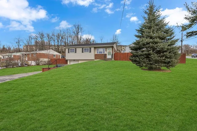 a view of a house with a big yard and large trees