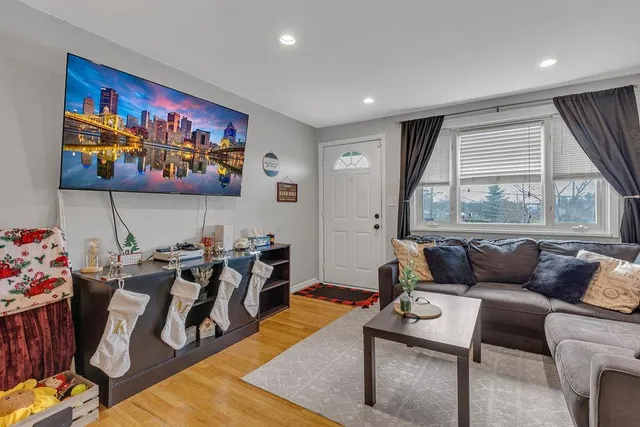 a living room with furniture a flat screen tv and a floor to ceiling window