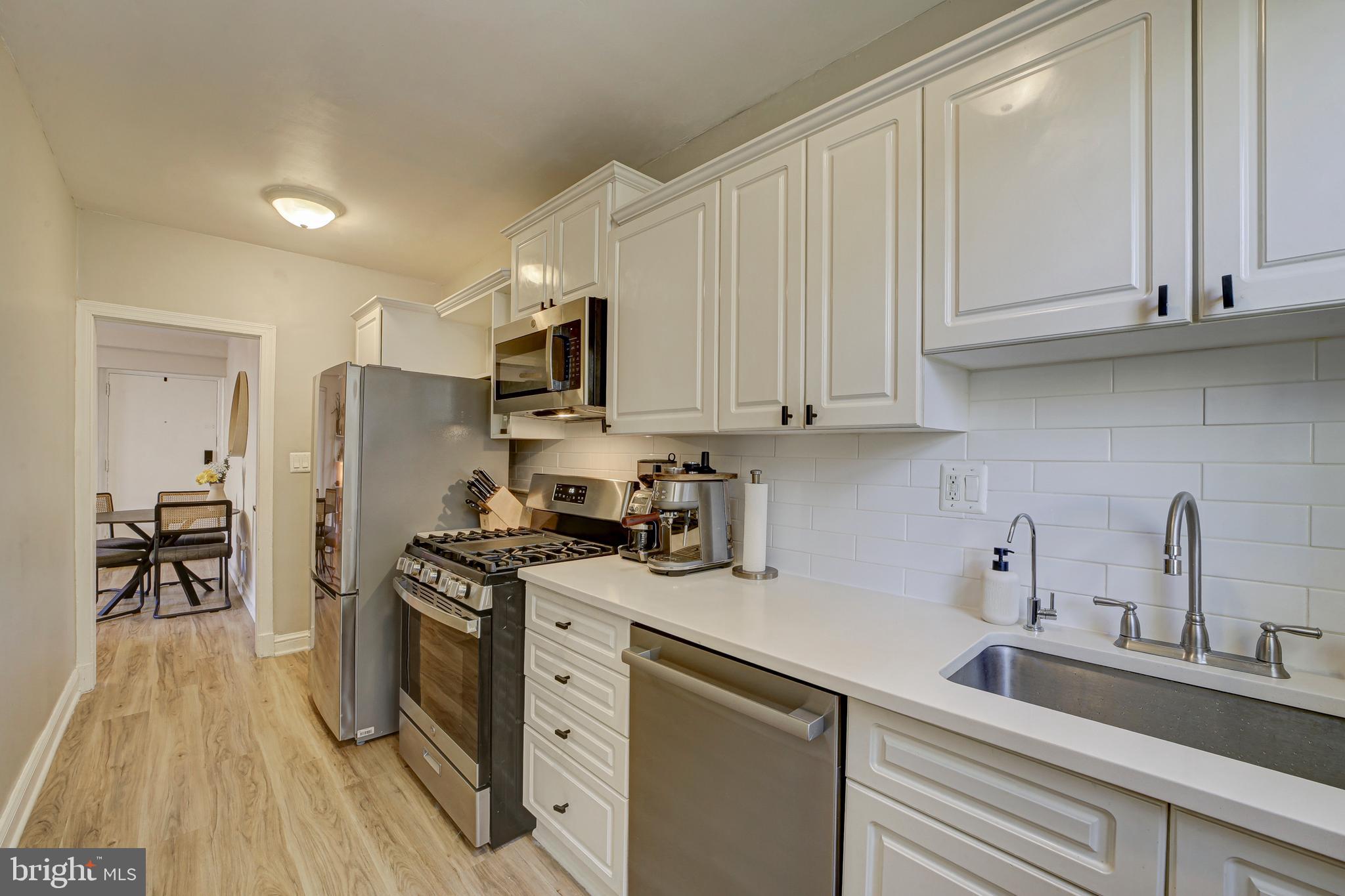 1404 Tuckerman Street Northwest, Unit 1 Washington, DC 20011 - Photo 7 of 18 a kitchen with stainless steel appliances granite countertop a sink dishwasher a refrigerator and cabinets with wooden floor