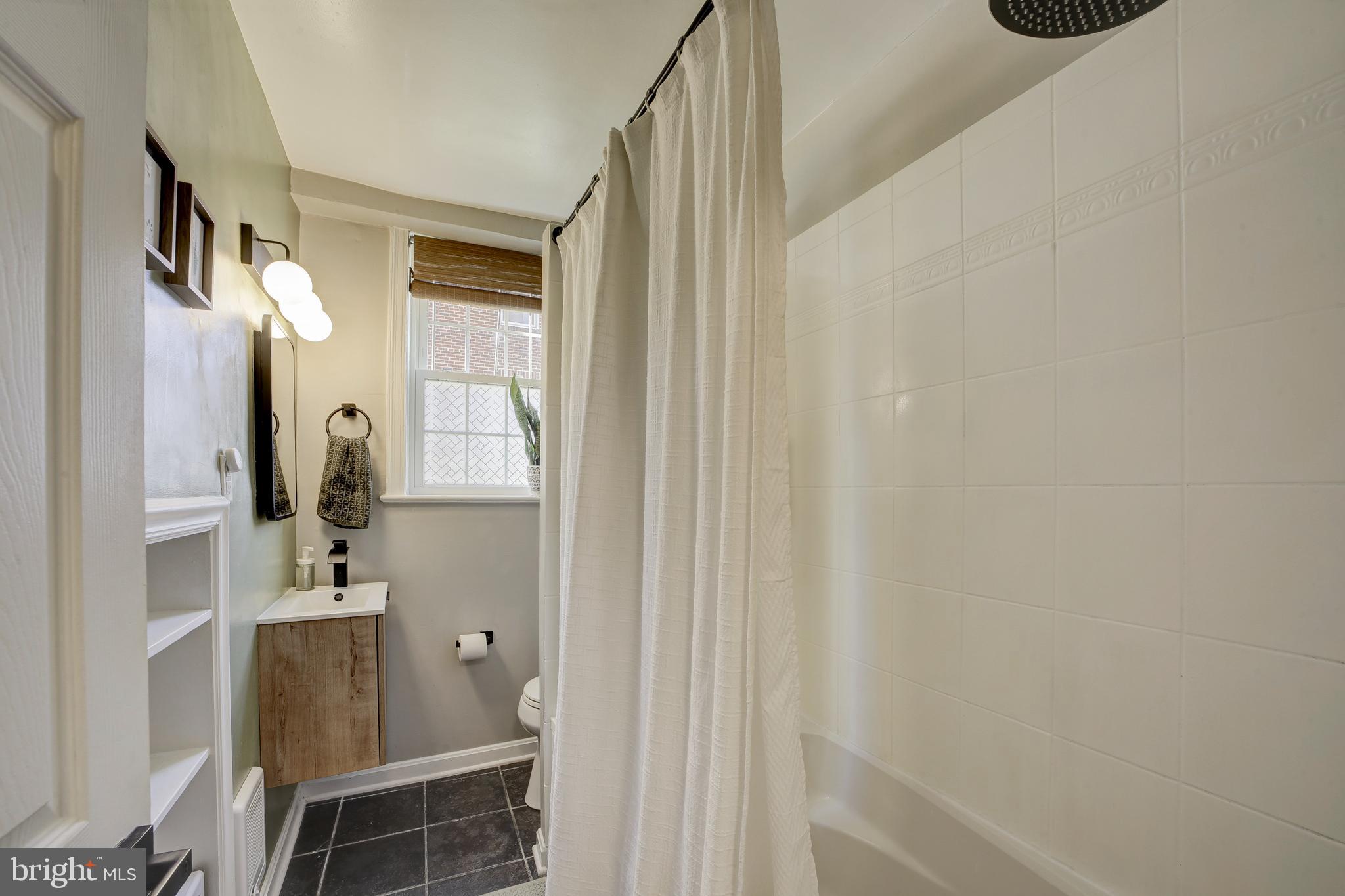 1404 Tuckerman Street Northwest, Unit 1 Washington, DC 20011 - Photo 8 of 18 a bathroom with a sink and mirror with bathtub