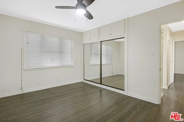 an empty room with wooden floor cabinet and windows