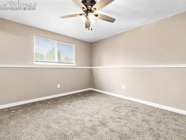 an empty room with a window and ceiling fan