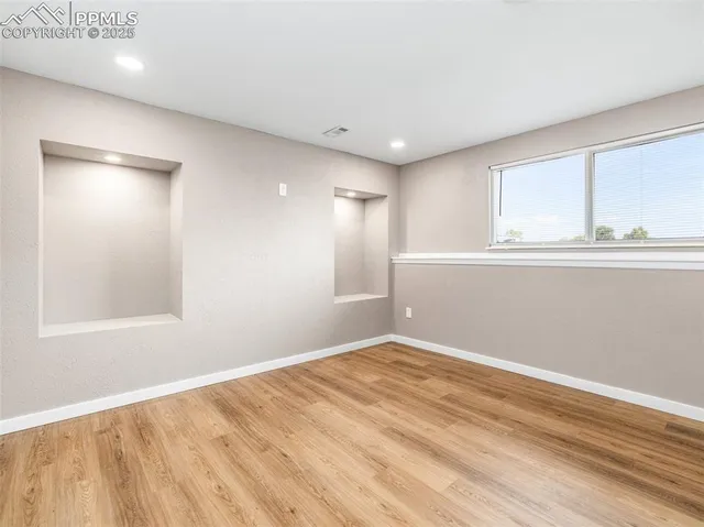 a view of empty room with wooden floor and fan