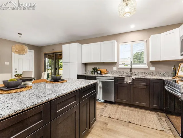 a kitchen with granite countertop stainless steel appliances sink stove and cabinets
