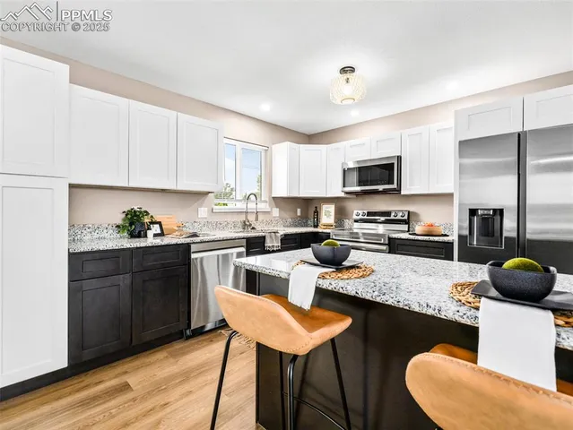 a kitchen with a refrigerator a stove a sink dishwasher a dining table and chairs with wooden floor