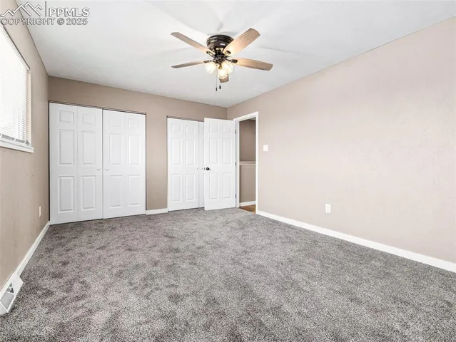 an empty room with closet and a ceiling fan