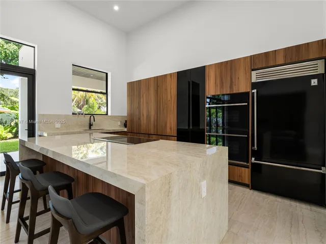 a large kitchen with stainless steel appliances a large counter top a sink and a couch