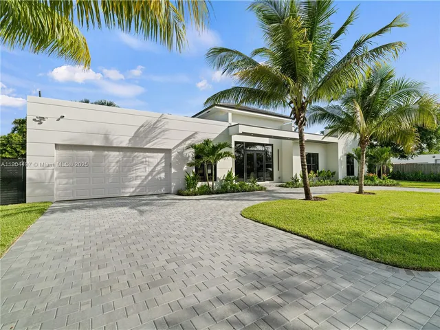 a front view of a house with a garden and trees