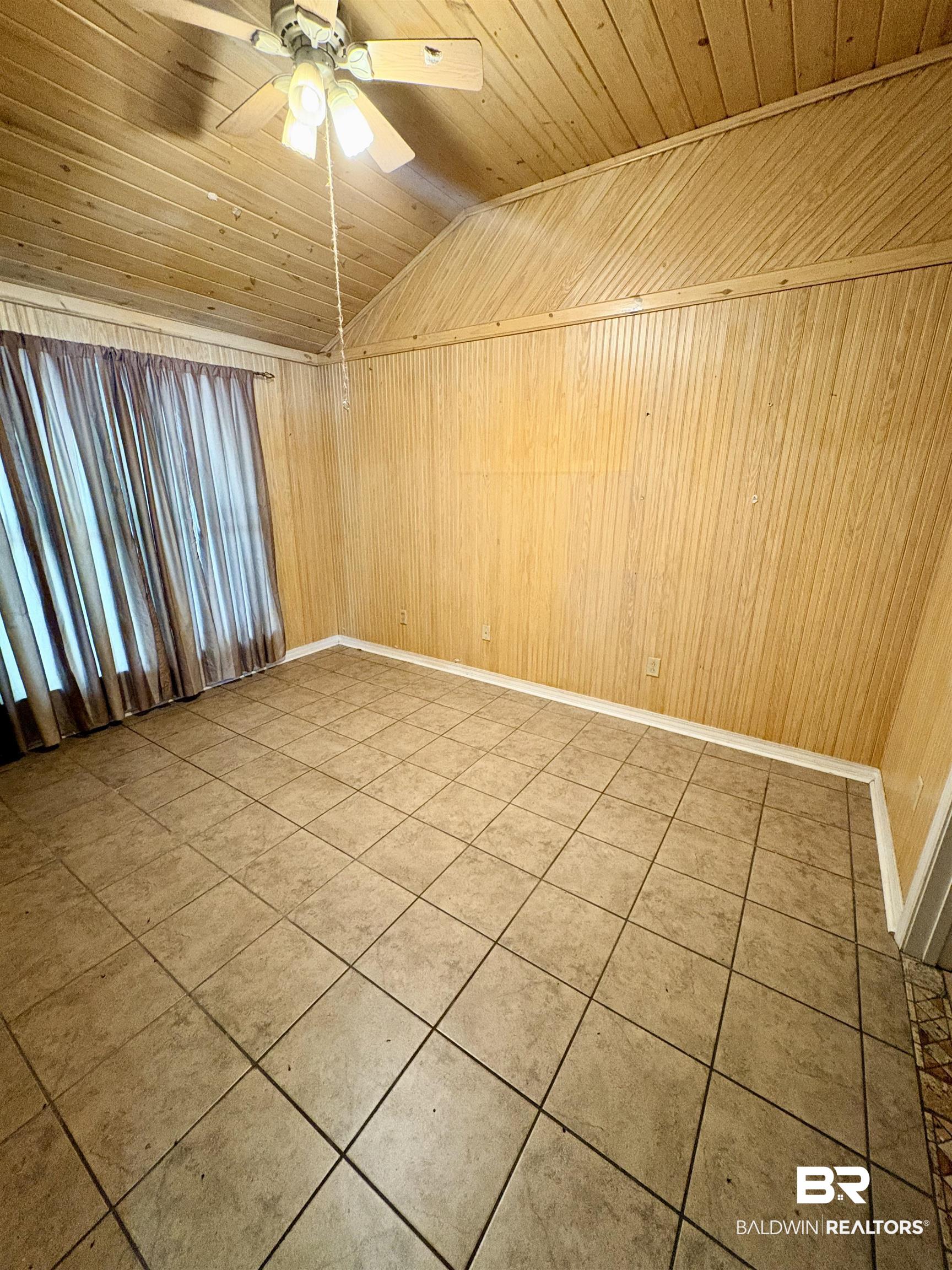 1018 Bates Road Evergreen, AL 36401 - Photo 4 of 21 Unfurnished room with a ceiling fan, a vaulted wood ceiling, tile patterned flooring, and wood walls