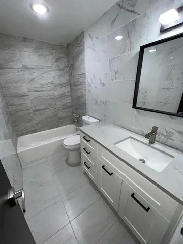 a bathroom with a granite countertop sink a toilet and a mirror