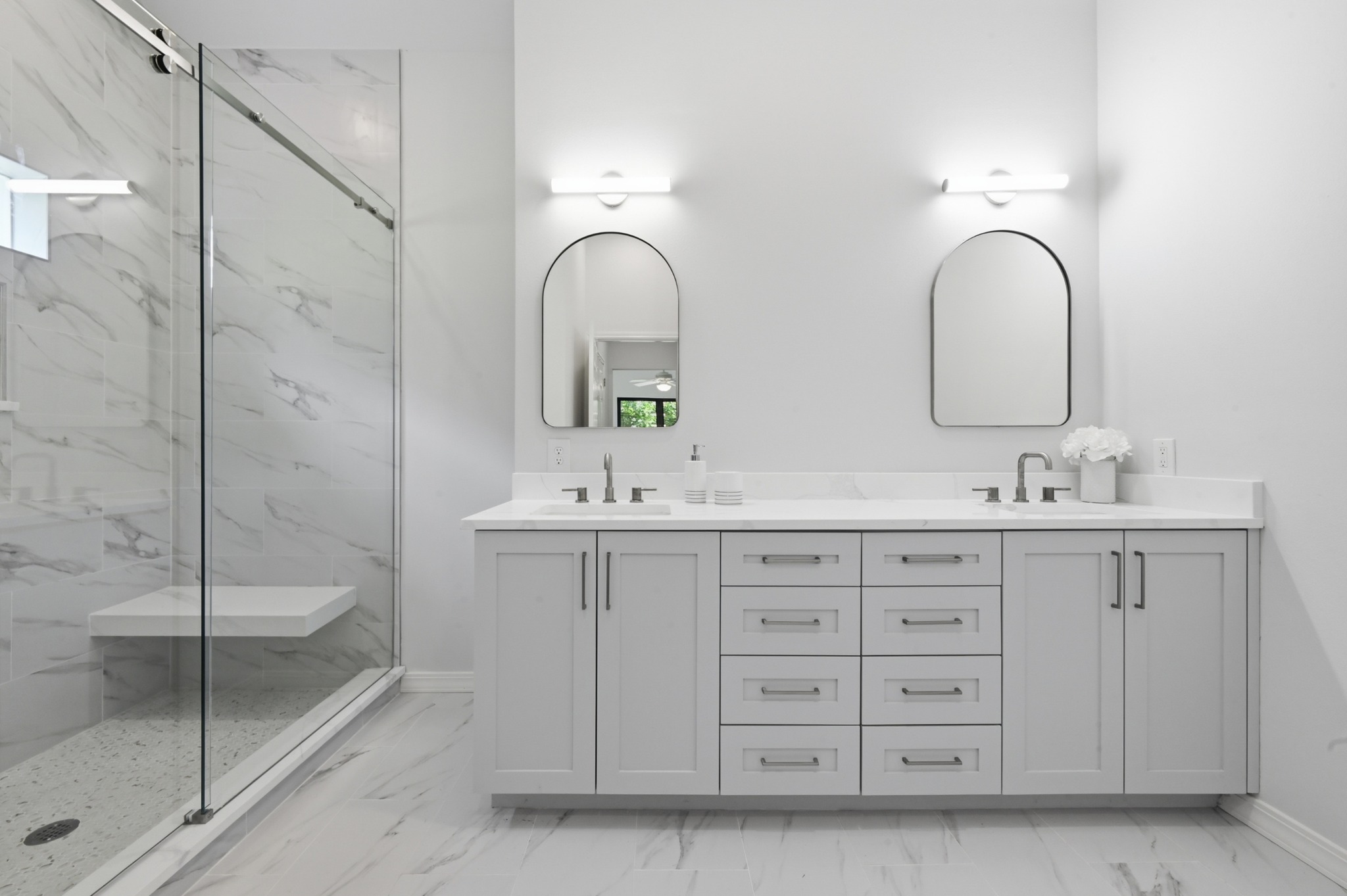 1107 Bowie Road Austin, TX 78733 - Photo 21 of 40 Marble-look tile flooring grounds a pristine bathroom featuring a dual vanity and glass-enclosed shower.