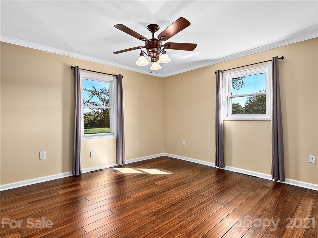588 Lee Cudd Road Rutherfordton, NC 28139 - Photo 10 of 42 an empty room with wooden floor chandelier fan and windows
