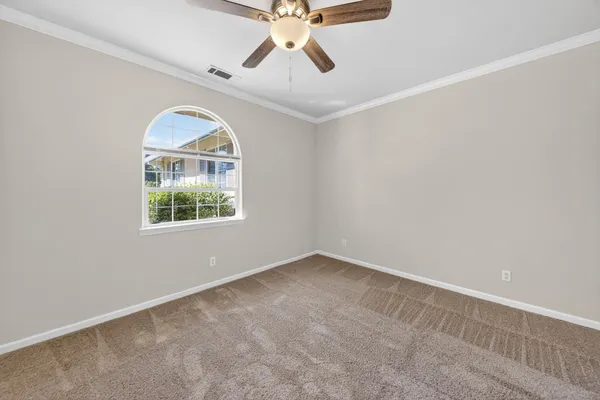 an empty room with windows and ceiling fan