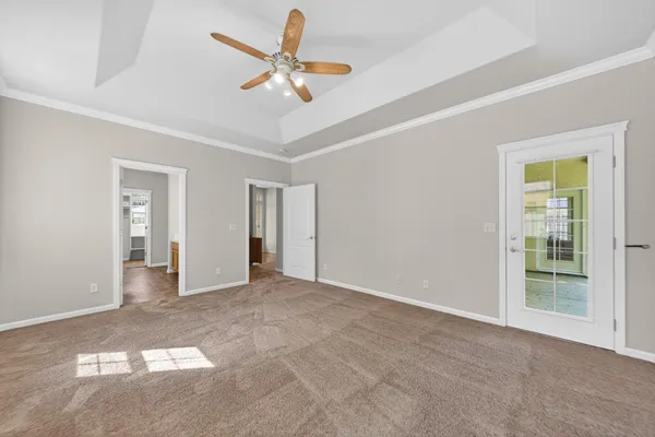 an empty room with chandelier fan and windows