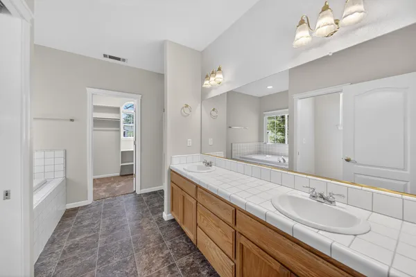 a spacious bathroom with a granite countertop double vanity sink a mirror and a shower